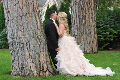 Bride and groom kissing next to a tree