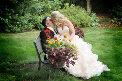 Bride and groom sitting on a bench kissing